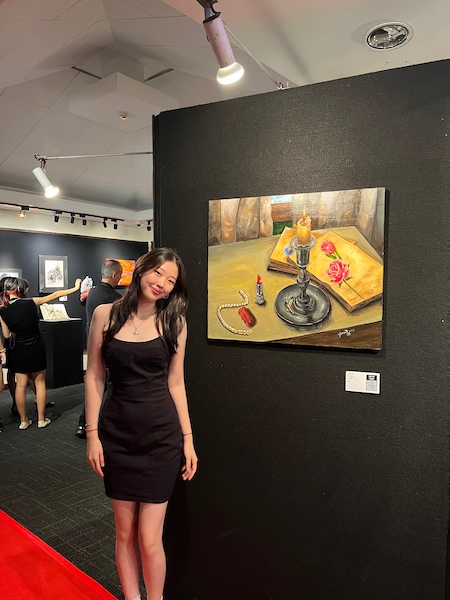 Yuna standing next to her painting